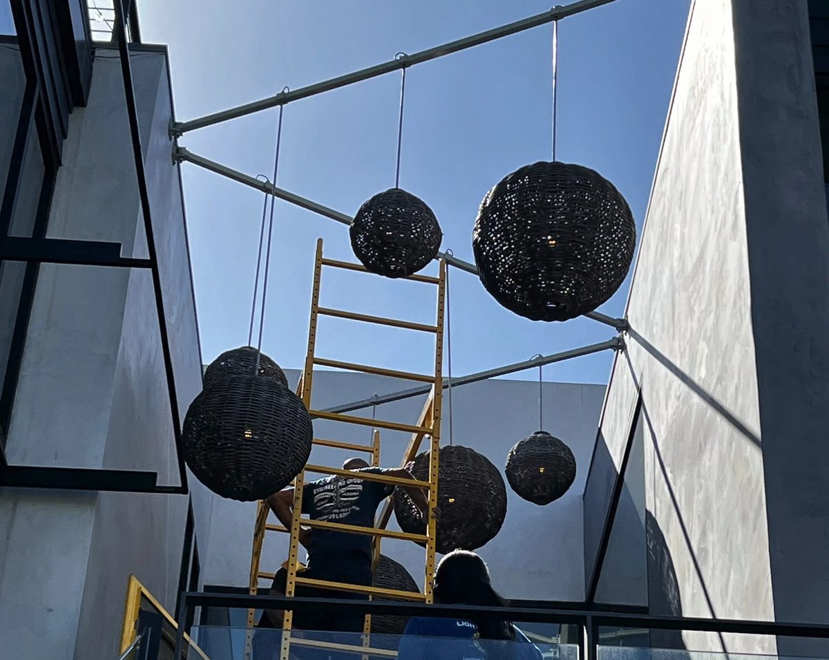 Woven lanterns hung over a courtyard, installed from a scaffold